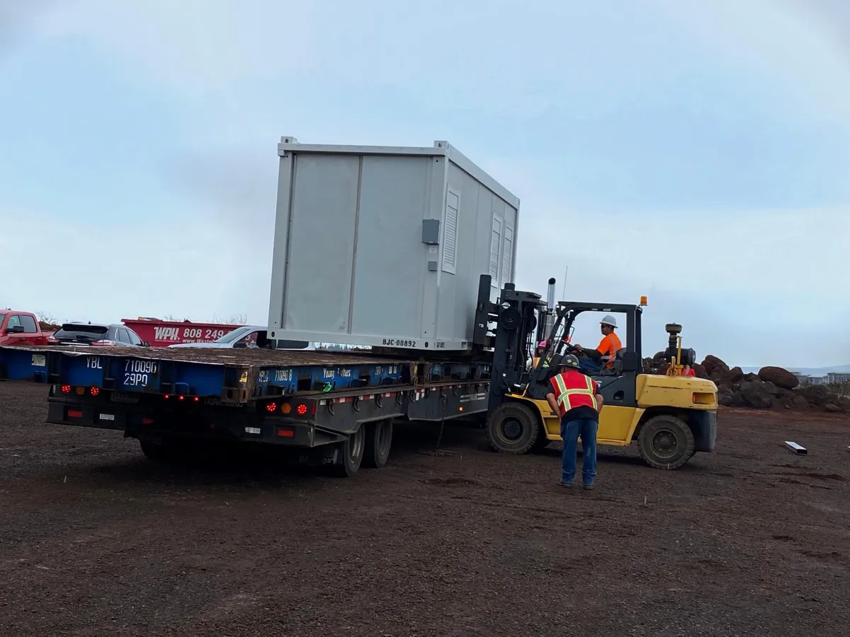 Forklift loading a modular unit onto a flatbed trailer