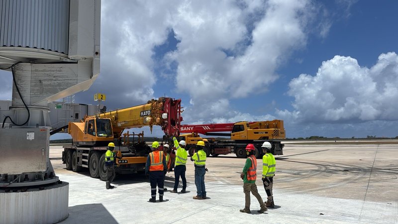Workers with KATO and SANY cranes at airport