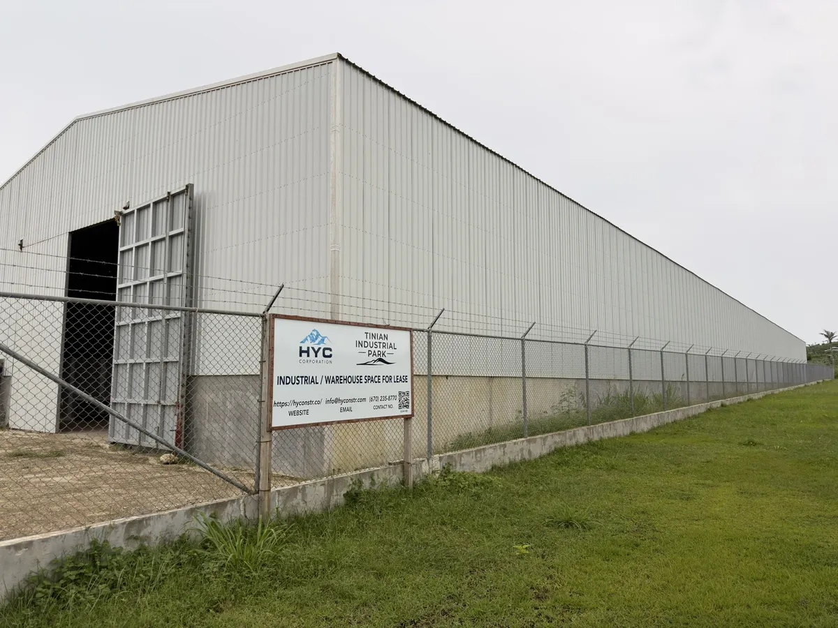 Exterior of the HYC warehouse on Tinian with HYC sign on the security fence